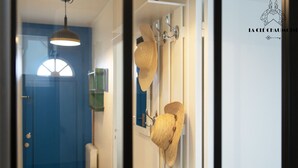 A hallway with a blue door, a hanging light fixture, and a wall-mounted hat rack.