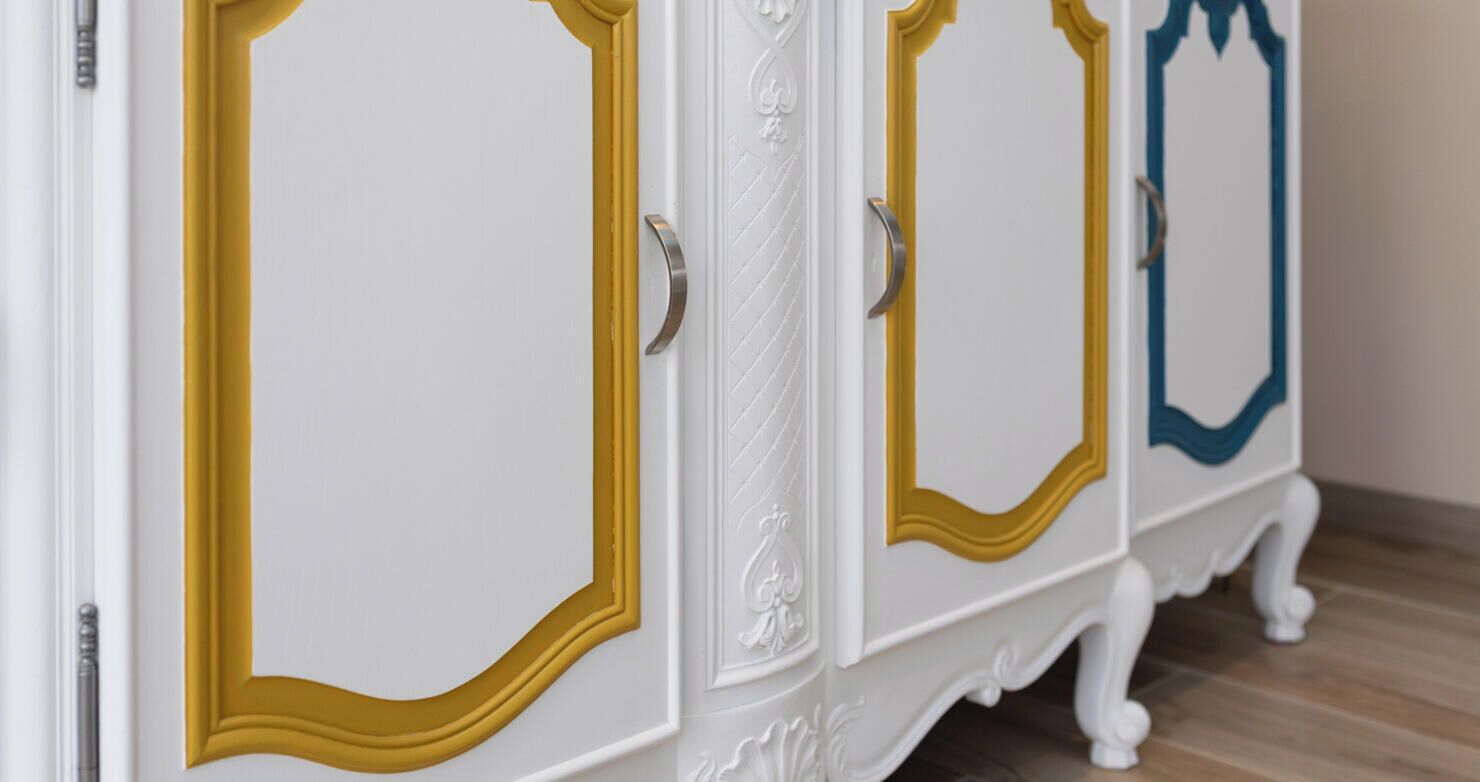 Un mueble blanco con molduras decorativas doradas y azules.