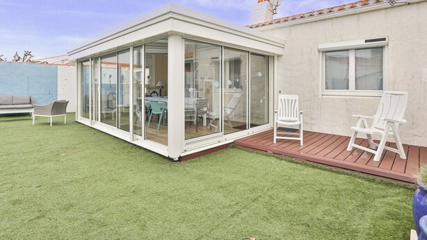 A covered patio with glass doors, a wooden deck, and outdoor furniture.