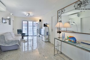 A modern living room with a sofa, a glass coffee table, a TV, and a decorative fish.