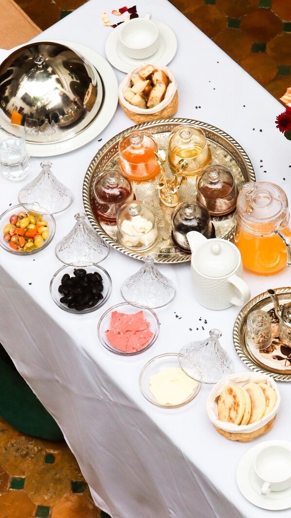 A table set with various food items and drinks, including a teapot, a pitcher, and several bowls containing different foods. - ABBASSIA Marrakech (Marrakech)
