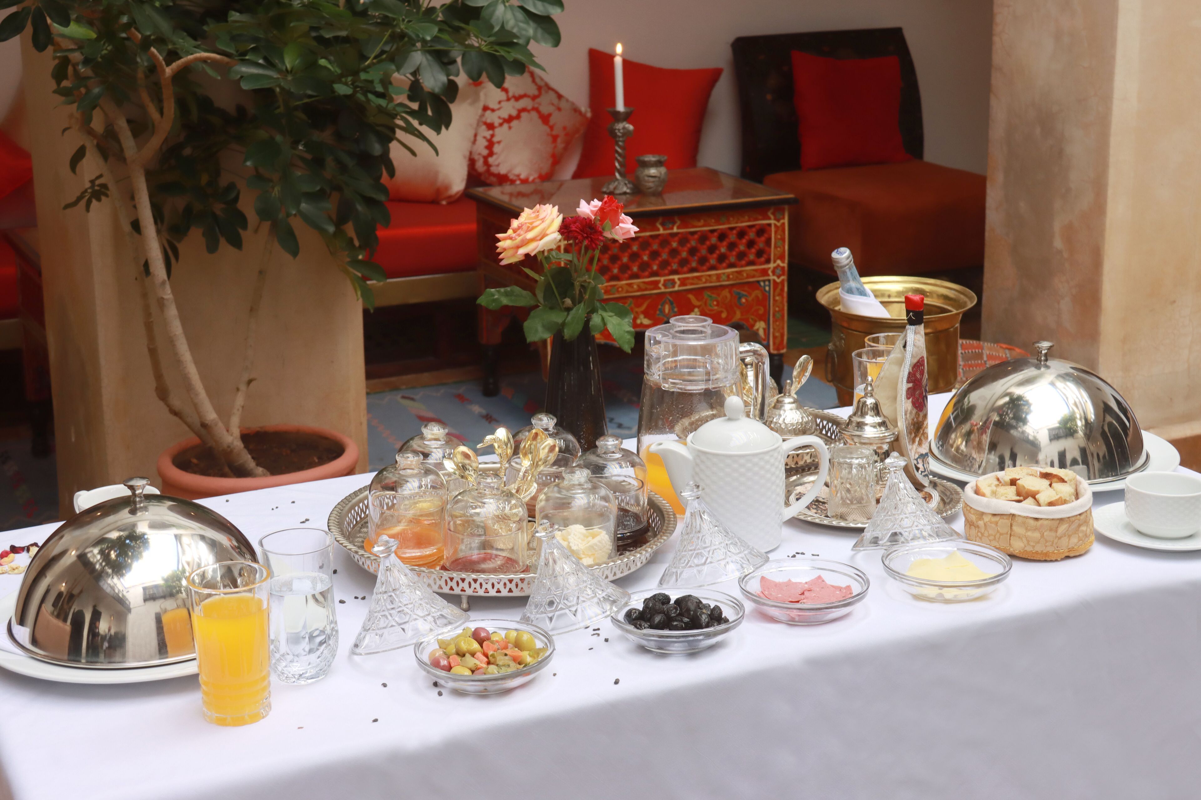 Une table de petit-déjeuner avec divers aliments, une plante en pot et un canapé rouge en arrière-plan.
