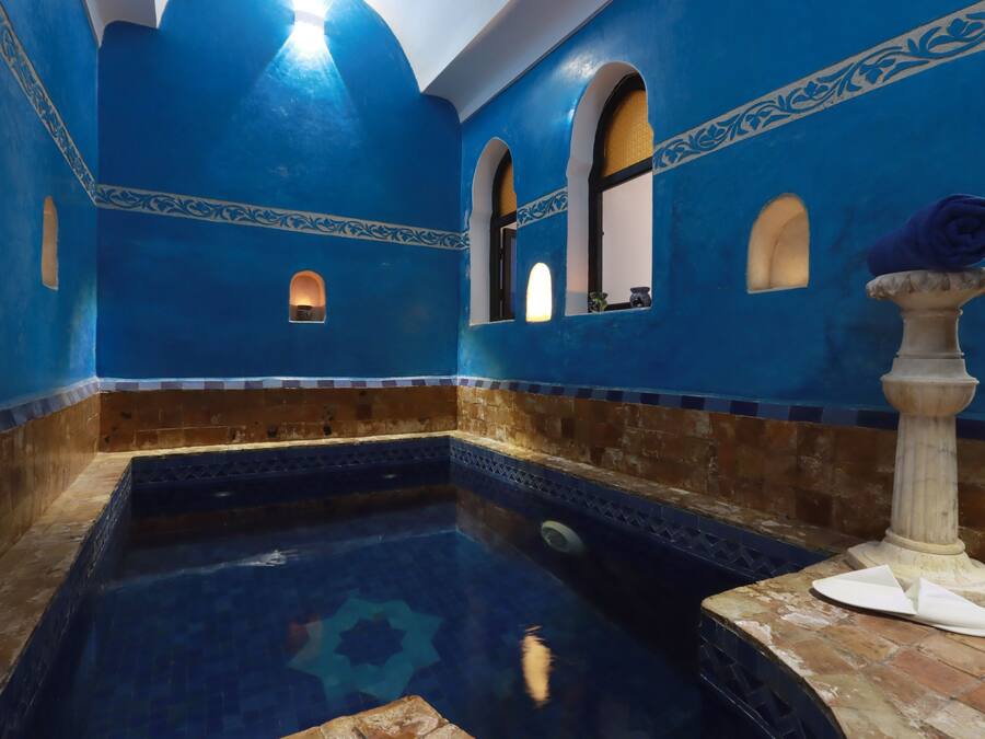 A room with a pool, blue walls, and a decorative pillar.