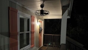 A wooden deck with a ceiling fan, a door with a light, and a railing. - Hidden in Paradise/ Pet friendly/ private house! (Gulf Shores)