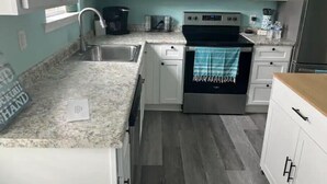 A kitchen with white cabinets, a stainless steel sink, a microwave, an oven, and a refrigerator. - Hidden in Paradise/ Pet friendly/ private house! (Gulf Shores)
