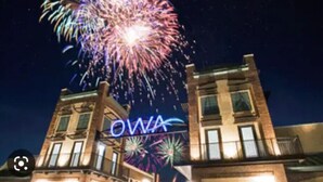 A building with a sign that reads "OWA" against a night sky with fireworks. - Hidden in Paradise/ Pet friendly/ private house! (Gulf Shores)