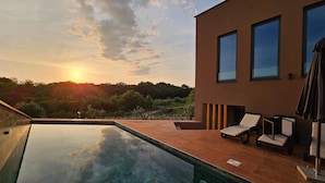 A modern outdoor pool area with a clear view of the sunset and surrounding greenery. - Nice home in Stancijeta (Stancijeta)