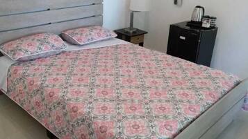 A bedroom with a bed, a nightstand, a lamp, and a small cabinet.