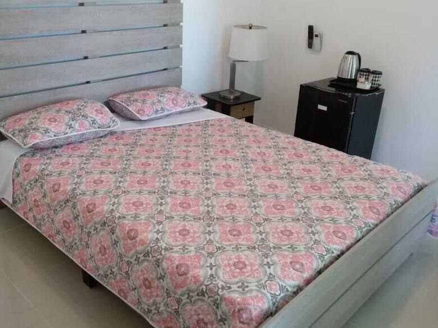A bedroom with a bed, a nightstand, a lamp, and a small cabinet.