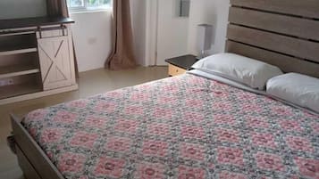 Un dormitorio con una cama de madera, una mesita de noche, una ventana con cortinas y una puerta.