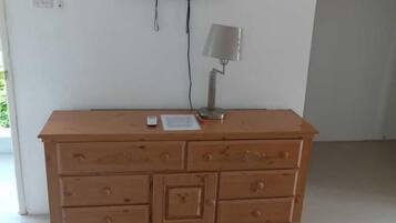 Uma cômoda de madeira com gavetas e uma TV de tela plana presa na parede acima.