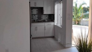 Eine moderne Küche mit weißen Schränken, einer Granitabdeckung und einem Fenster mit Jalousien.