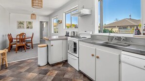 Una cocina moderna con armarios blancos, un ventanal y vistas a una casa.
