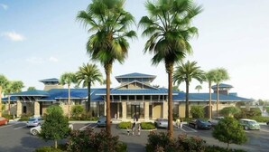 A hotel with a modern design, featuring a central entrance flanked by palm trees, a parking lot, and a clear sky. - Luxury 5BR Townhome: Private Pool & Resort Fun - 117 JW (Davenport)