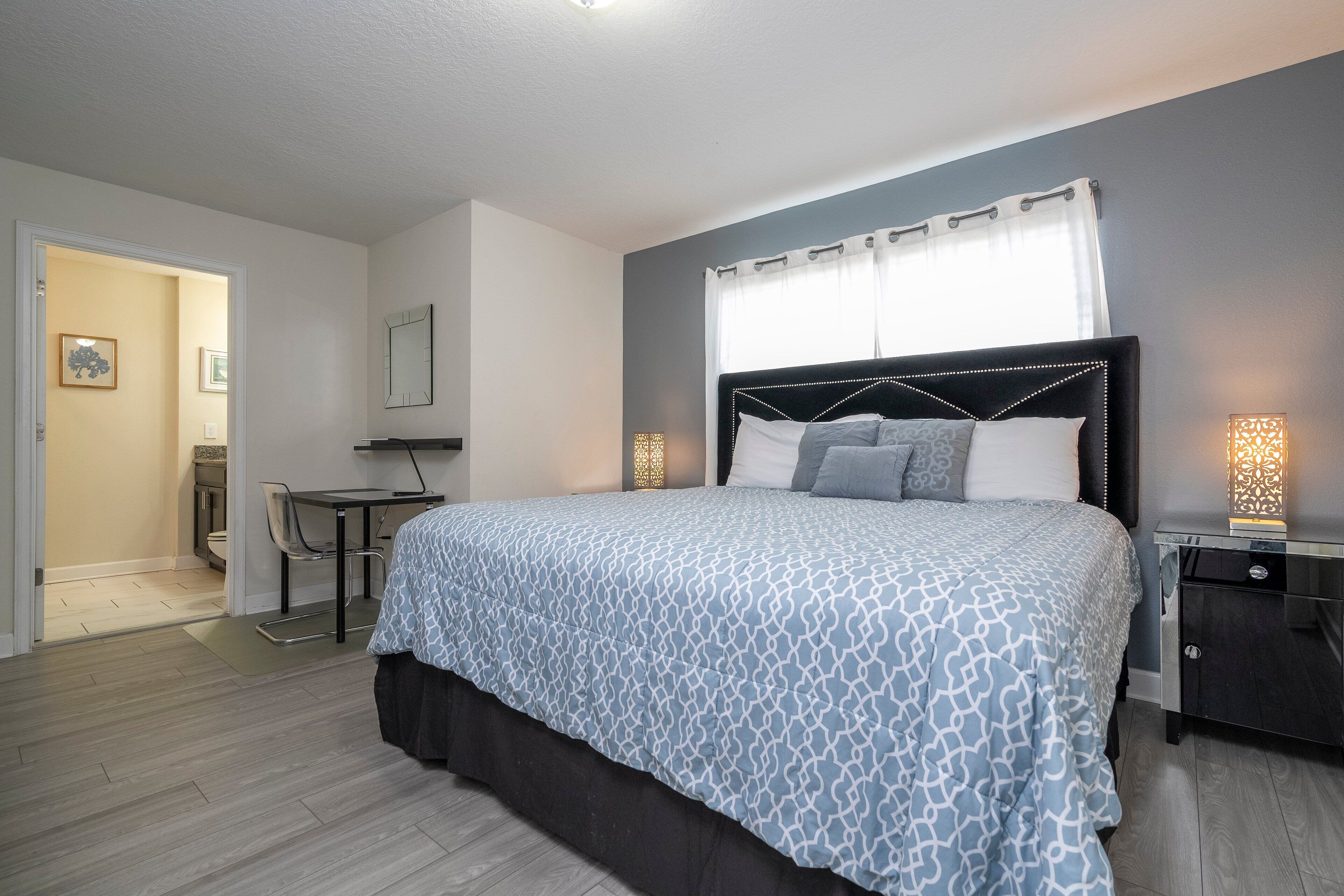 Une chambre à coucher avec un lit, des tables de chevet, un bureau et une chaise.