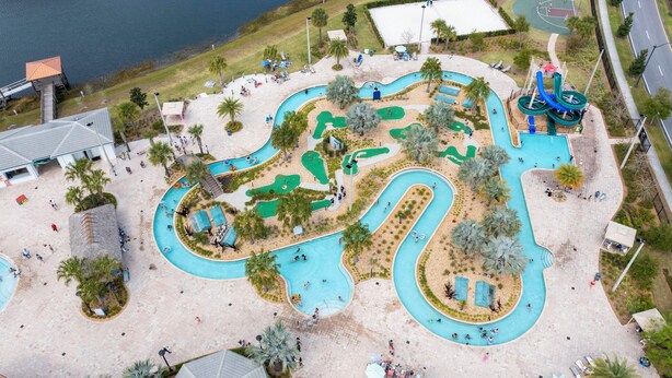 An aerial view of a water park with multiple pools, slides, and a basketball court.
