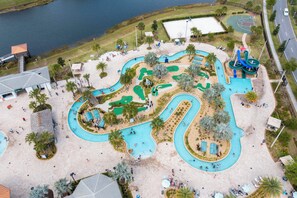 An aerial view of a water park with multiple pools, slides, and a basketball court.