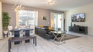 A modern living room with a dining area, a sofa, a TV, and a large window.