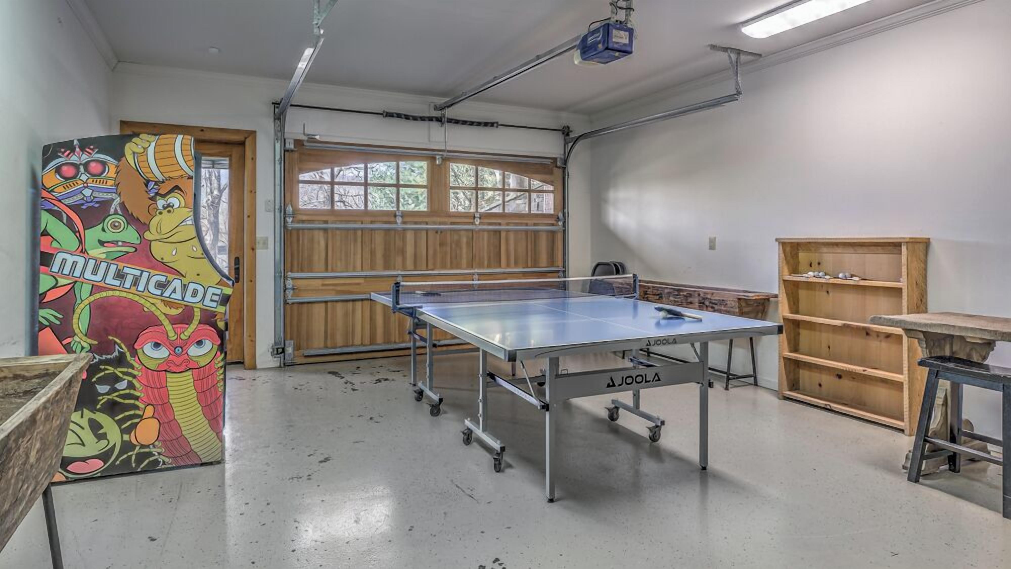 A room with a ping pong table, a wooden door, and a mural on the wall.