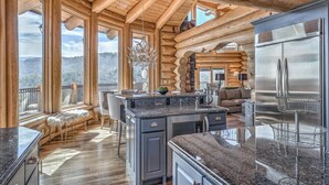 Una cocina amplia con una isla grande, encimeras de granito y un refrigerador de acero inoxidable.