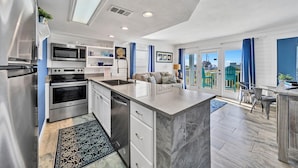 A modern kitchen with built-in appliances, a dining area with a view, and a balcony with outdoor seating. - Beach Service Included! 100 Yards To Private Beach! Gulfview I 112 (Destin)