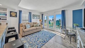 A modern living room with a beige sofa, a blue patterned rug, and a glass dining table. - Beach Service Included! 100 Yards To Private Beach! Gulfview I 112 (Destin)