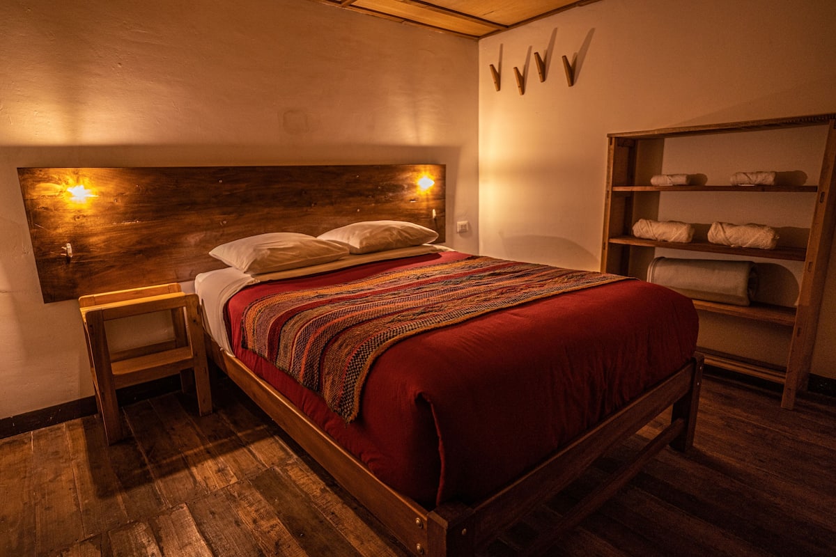 Ein Bett mit Holzkopf, ein Nachttisch und ein Regal mit Handtüchern.