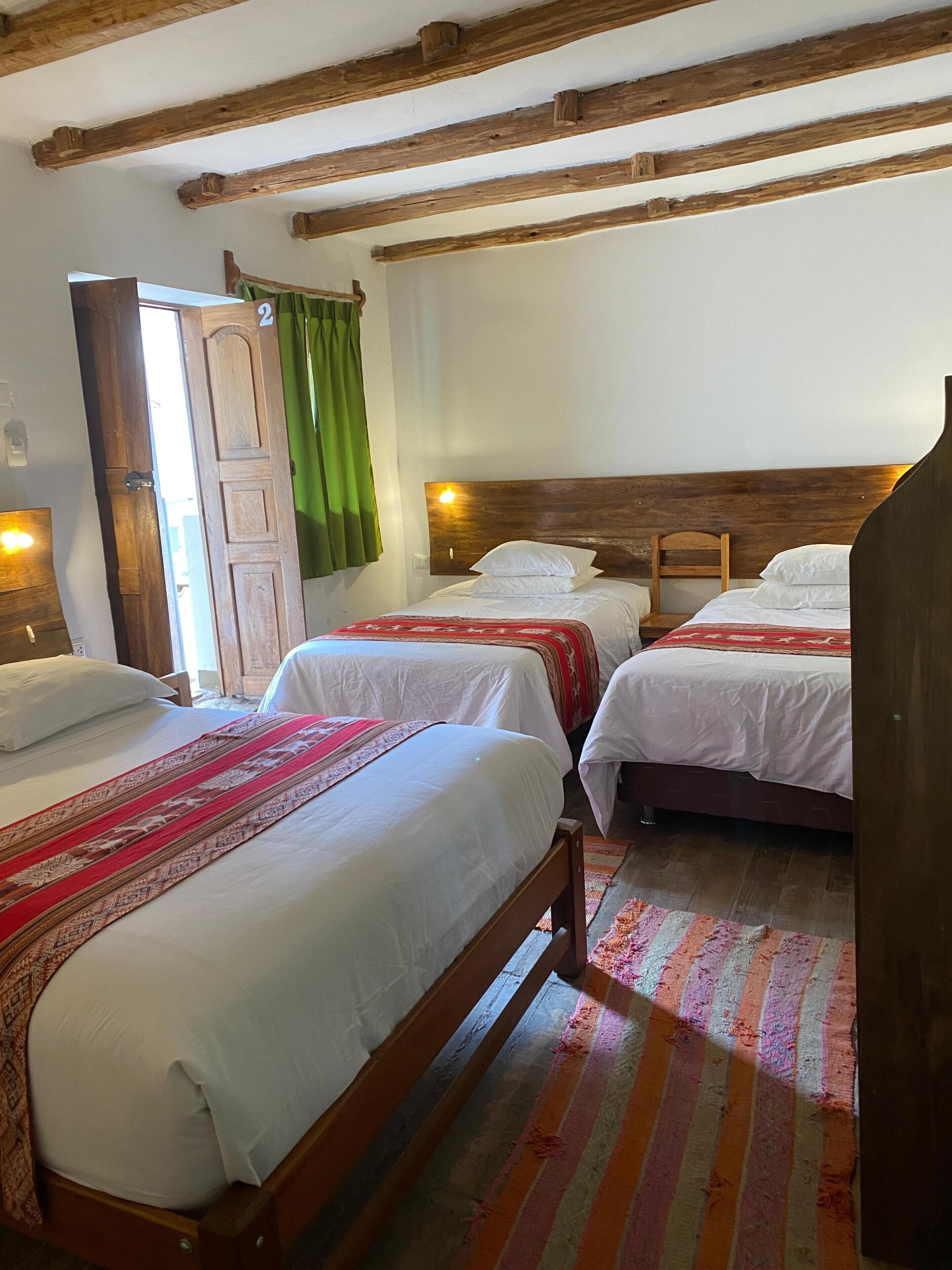 A room with two wooden beds, a green curtain, and a wooden ceiling.