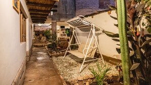 A narrow alleyway with a swing chair, a cactus, and a stone wall. - MAMA GREEN Eco Lodge l Permaculture Farm l Farm To Table (Urubamba)