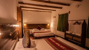 A hotel room with two beds, wooden beams on the ceiling, a green curtain, and a rack with towels. - MAMA GREEN Eco Lodge l Permaculture Farm l Farm To Table (Urubamba)