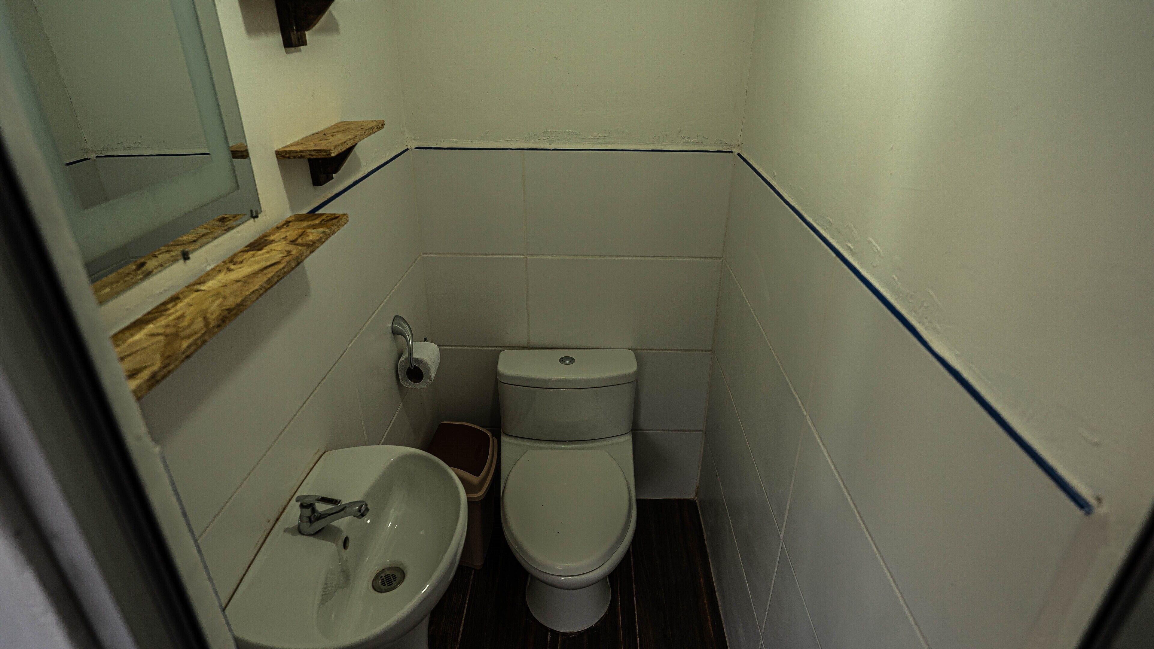 A small bathroom with a toilet, sink, and a mirror.