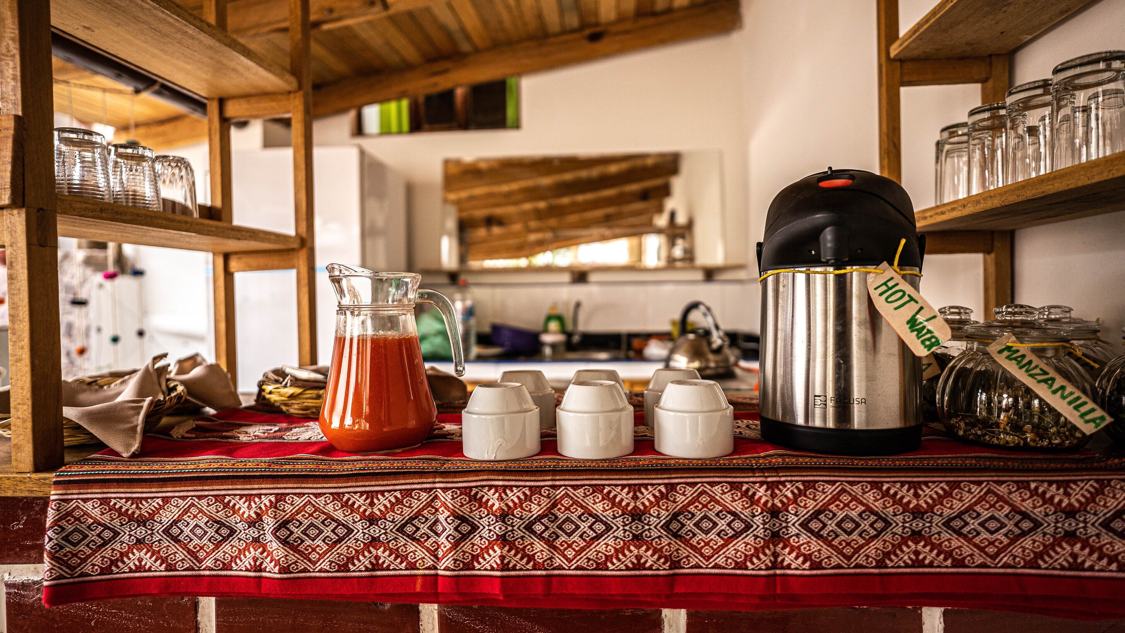 A kitchen area with a coffee maker, a pitcher of tea, and several jars on shelves.