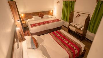 Habitación de hotel con dos camas, cabecero de madera, cortina verde y repisa con toallas.