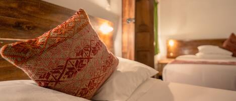 Una habitación de hotel con cabecera de madera, almohada decorativa estampada y cama bien hecha con sábanas blancas.