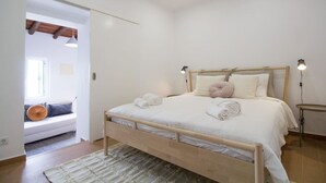 A bedroom with a wooden bed, white bedding, and a bedside table with two lamps. - Comfortable getaway in Medieval Castro Marim by Lisbeyond (Castro Marim)