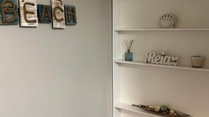 Ein Zimmer mit weißer Wand, einem Regal mit Dekoration und einem Schild mit Buchstaben.