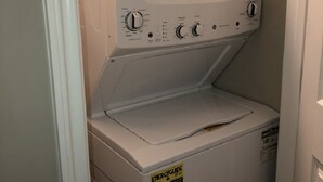 Uma máquina de lavar e secar compacta, com painel de controle, etiqueta de eficiência energética e puxador de porta.