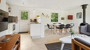 A modern kitchen with a central island, dining area with chairs, a sofa, and a fireplace. - 3 bedroom amazing home in Børkop (Børkop)