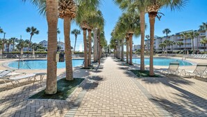 A poolside area with palm trees, lounge chairs, and a clear blue sky. - Steps from the Beach ~ 1st floor w/ pool view~ Amalfi Coast (Miramar Beach)