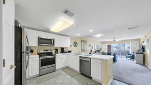 A modern kitchen with white cabinets, stainless steel appliances, and a large island. - Steps from the Beach ~ 1st floor w/ pool view~ Amalfi Coast (Miramar Beach)