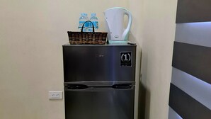 A compact refrigerator with a water dispenser and a kettle on top, placed against a wall with a striped pattern. - Grace & RB Hotel (Kalibo)