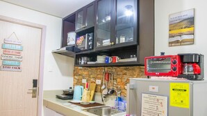 A kitchen with a countertop, a sink, a toaster, a coffee maker, and a refrigerator. There are cabinets above the countertop and a wall-mounted shelf. - Stylish 1BR Retreat at Trees Residences — Fast WiFi, Smart TV, Near SM Fairview (Quezon City)