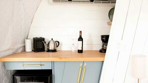 A compact kitchen with a wooden countertop, a black refrigerator, a light blue cabinet, and a white ceiling.
