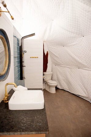 A compact bathroom with a sink, toilet, and shower area.