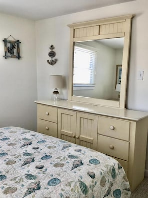 Un dormitorio con cama, cómoda, espejo y ventana.
