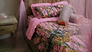 A bed with a wooden headboard, pink bedding, and a canopy. - Where Friends and Family make Memories. (South River)