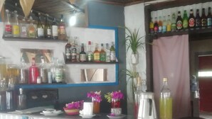 Una zona de bar con estantes llenos de botellas de licores, una máquina de café y flores decorativas.