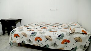 Une pièce avec un lit, une petite table et une prise électrique au mur.