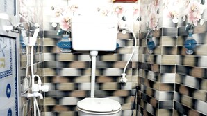 Une salle de bain avec des toilettes, une douche et des murs carrelés.