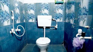 Une salle de bain comprenant des toilettes, une douche et un bidet. Les murs sont recouverts de carreaux décorés d’un motif floral.